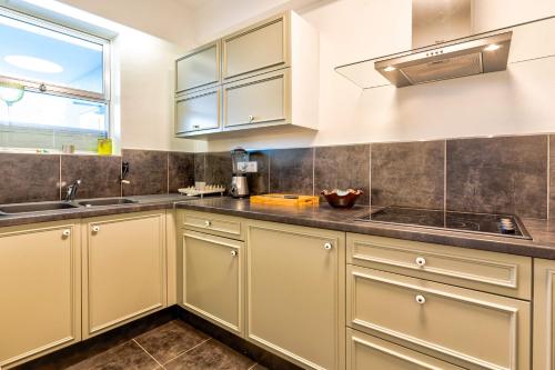 une cuisine avec des armoires blanches, un évier et une fenêtre dans l'établissement Annabelle, à Villeneuve-Loubet