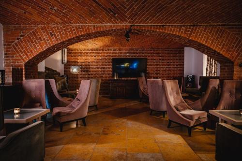 a room with chairs and a television and a brick wall at Hanza Pałac Wellness & SPA in Warlubie