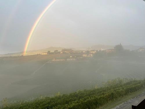 a rainbow in the sky over a field and a lake at Red Wine Camere in La Morra