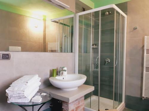 uma casa de banho com um lavatório e uma cabina de duche em vidro. em Red Wine Camere em La Morra