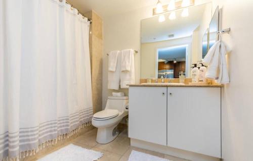 a bathroom with a toilet and a sink and a mirror at Tropical Coastal Resort in Boynton Beach