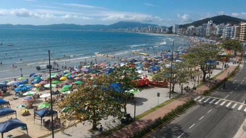 a beach with umbrellas and people on the beach at Apartamento de Cobertura frente para o mar Itapema in Itapema