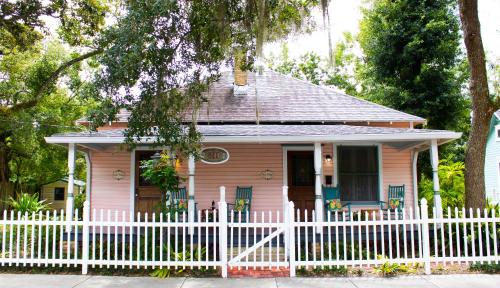 a small pink house with a white fence at Sweetwater Branch Inn in Gainesville