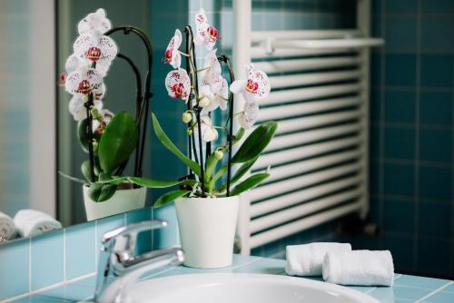 a white vase with flowers sitting on a bathroom sink at La Dolce Vita in Montecchia di Crosara
