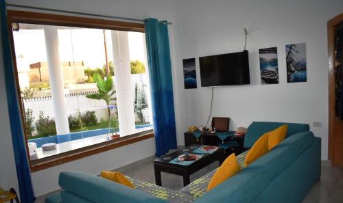 a living room with a blue couch and a tv at The House Of Lights in Luxor