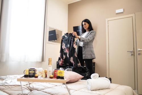 a woman standing in front of a mirror holding a jacket at B&B De Nava Suite in Reggio Calabria