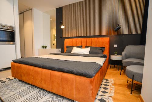 una camera da letto con un grande letto arancione e una sedia di Design Apartment near Gorica Park a Podgorica