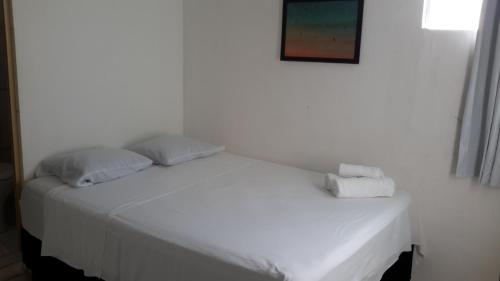 a white bed with two pillows on top of it at Pousada Mirante de Porto in Porto De Galinhas