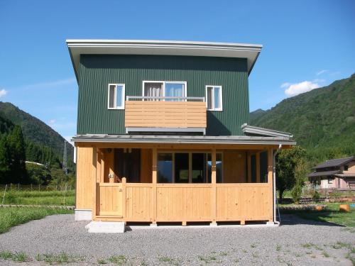 a green house with a porch and a balcony at Gujo Cottage Ryukobashi no Hotori - Vacation STAY 88697v in Gujo