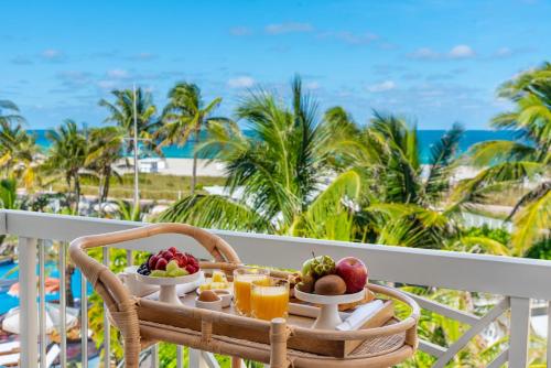 uma mesa com frutas numa varanda com vista para a praia em The Savoy Hotel & Beach Club em Miami Beach