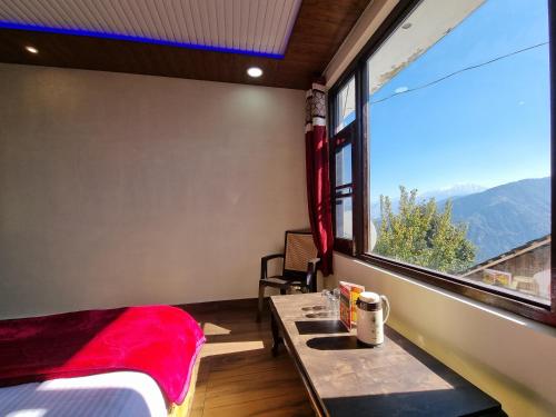 a room with a bed and a table and a window at Grand Kailash Khajjiar in Dalhousie