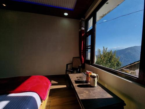 a room with a bed and a table with a window at Grand Kailash Khajjiar in Dalhousie