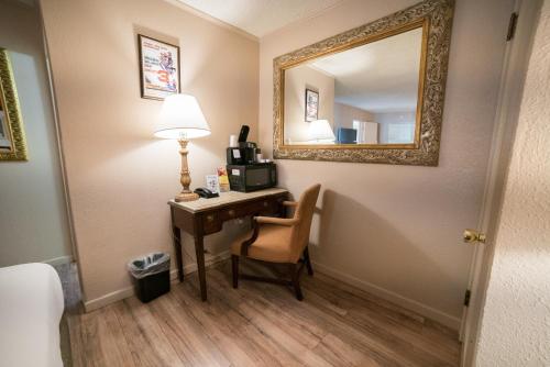 a room with a desk with a lamp and a mirror at Parry Lodge in Kanab