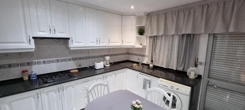 a white kitchen with white cabinets and a table at Paradisíaco. in Moncarapacho