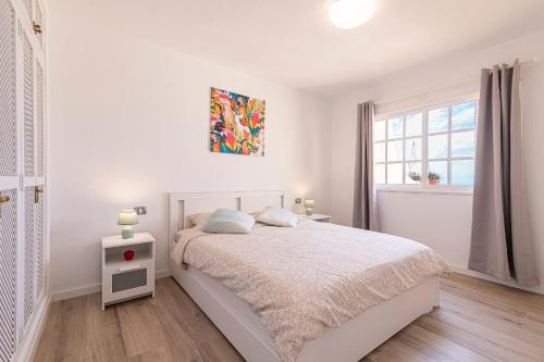 a white bedroom with a bed and a window at Top floor with ocean view in Adeje