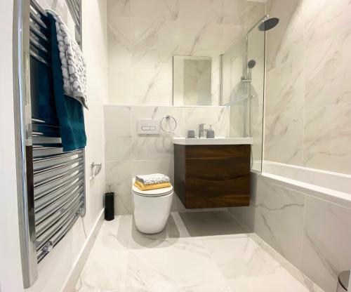a white bathroom with a toilet and a sink at Cloud at Fleet Heights Apartment Two in Fleet