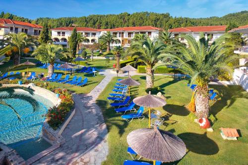 a resort with a pool and chairs and palm trees at Chrousso Village in Paliouri