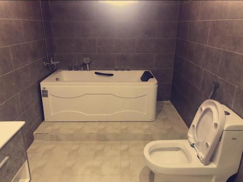 a bathroom with a bath tub and a toilet at فندق ادوماتو ADOMATo HOTEl in Dawmat al Jandal