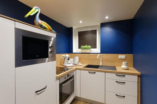 a kitchen with white cabinets and a bird statue on the counter at Romance spa tropical Le Havre in Le Havre