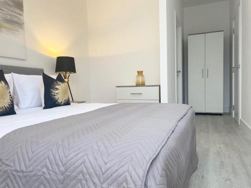 a white bedroom with a large bed and a lamp at Apex at Fleet Heights Apartment Five in Fleet