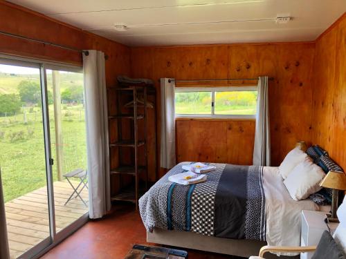 a bedroom with a bed and a sliding glass door at Bungalow de campo Nabucco - sierras, naturaleza y descanso in Minas