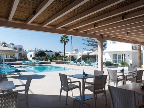 een patio met tafels en stoelen en een zwembad bij Diogenis Village Mykonos in Glastros