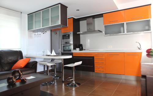 uma cozinha com armários laranja e uma mesa e cadeiras em Apartamento Los Canarios em Corcubión