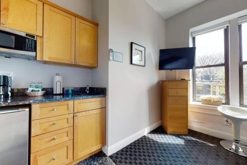 a kitchen with wooden cabinets and a sink and a window at Charming Studio in Boston Brownstone, #44 in Boston