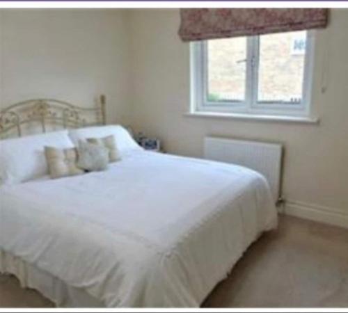 a white bed in a bedroom with a window at Cheerful 4- Bedroom Detached House with Portable in Addington