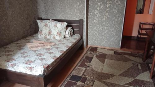 a small bedroom with a bed with pillows and a rug at Готель Адріана in Dunaivtsi