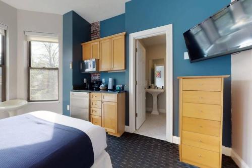 a bedroom with blue walls and a bed and a kitchen at Cozy Downtown Boston Studio, #45 in Boston