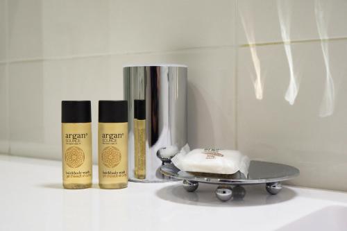 une étagère avec trois bouteilles de savon et un skateboard dans l'établissement Duomo Luxury Apartment VI, à Milan