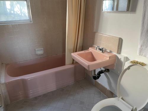 a bathroom with a sink and a toilet and a tub at La Casa Motel, Garden Grove - Anaheim in Garden Grove