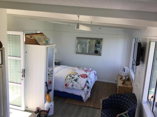 a small bedroom with a bed and a mirror at Sunset Cottage in Tauranga