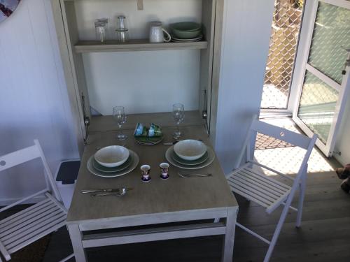 a table with plates and glasses on it with two chairs at Sunset Cottage in Tauranga