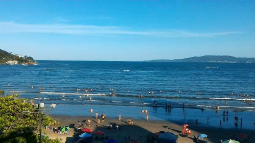 a group of people in the water at the beach at Apartamento de Cobertura frente para o mar Itapema in Itapema