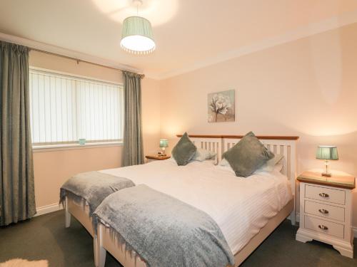 a bedroom with a large white bed with two pillows at Riverside Cottage in Portree