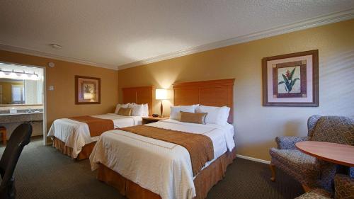 um quarto de hotel com duas camas e uma mesa em SFO El Rancho Inn SureStay Collection by Best Western em Millbrae