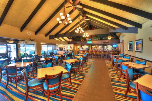 a dining room with tables and blue chairs at Best Western Aku Tiki Inn in Daytona Beach