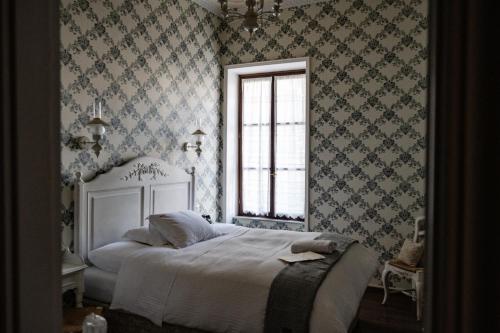 sypialnia z białym łóżkiem w pokoju z tapetą w obiekcie Boutique Hotel Anagennisis w mieście Pirgos
