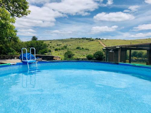 a large blue swimming pool with a hill in the background at Bungalow de campo Nabucco - sierras, naturaleza y descanso in Minas