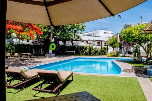 a swimming pool with two chairs and an umbrella at Hotel Medrano Temáticas and Business Rooms Aguascalientes in Aguascalientes
