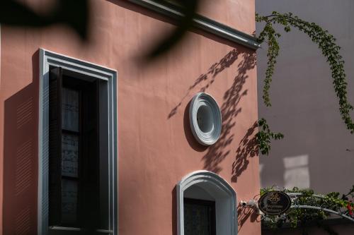 a pink building with a window and a clock on it at Boutique Hotel Anagennisis in Pýrgos