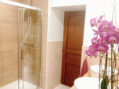 a bathroom with a shower and a vase of purple flowers at L’Alcalys - Maison de vacances au vert - Sans TV in Saint-Aignan