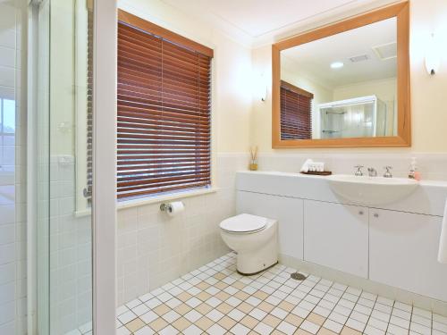 a bathroom with a toilet and a sink and a mirror at Villa 2br Prosecco Villa located within Cypress Lakes Resort in Pokolbin