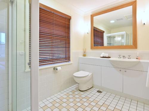 un bagno con un water, un lavandino e uno specchio di Villa 2br Prosecco Villa located within Cypress Lakes Resort a Pokolbin