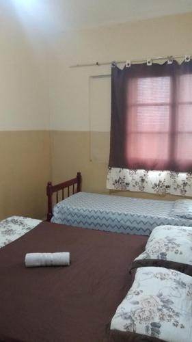 a bedroom with two beds and a window with a curtain at Hotel Brasil in Presidente Prudente