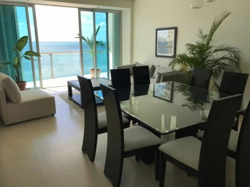 a dining room with a glass table and chairs at Ocean front apartment in Cancun in Cancún