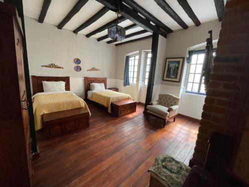 a bedroom with two beds and a chair in a room at Hotel Boutique Portal de Cantuña in Quito