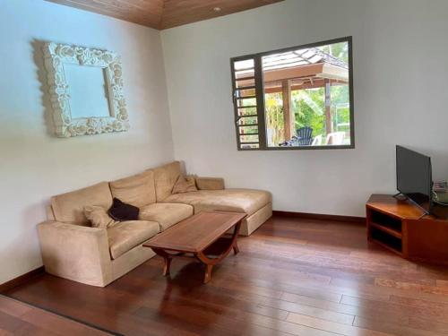 uma sala de estar com um sofá e uma mesa em Moorea Temae Villa walking dist beach and golf em Moorea